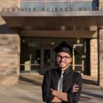 Luis Rodriguez wearing a graduation cap in front of the computer science building.