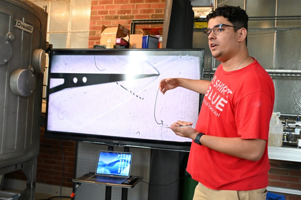 A student shows a tour group his lab's research
