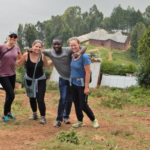 A group of five stand above a mountain lake in East Africa and smile