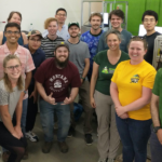 A group of 14 people stands in a lab at the Powerhouse