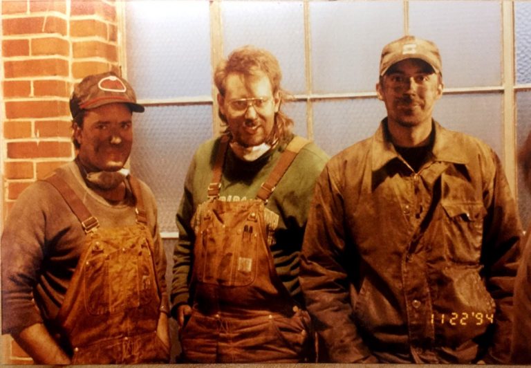 Three men covered in coal dust. Date on the photo reads November 22, 1994.