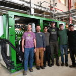 A group stands in front of the large green 2G engine in the EECL