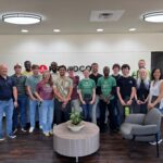 A group from the Powerhouse stands and poses for a photo in the lobby of Broadcom