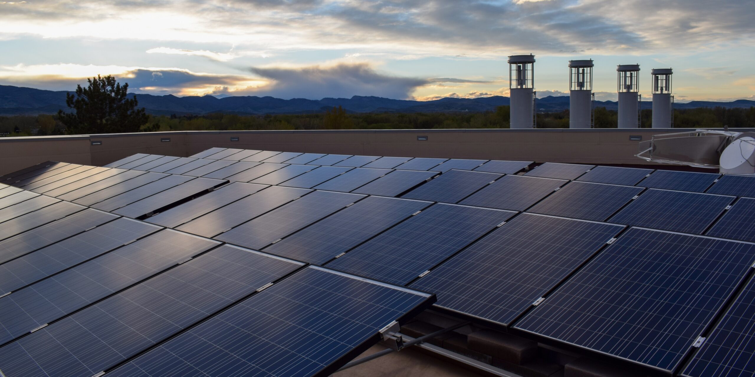 Solar panels on the roof of the Powerhouse with the vertical access wind turbines in the background.