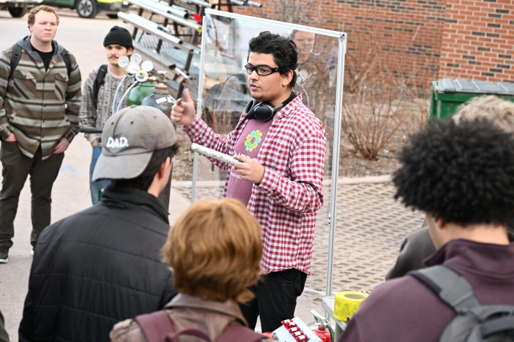 Students stand around as Manav gives a demonstration