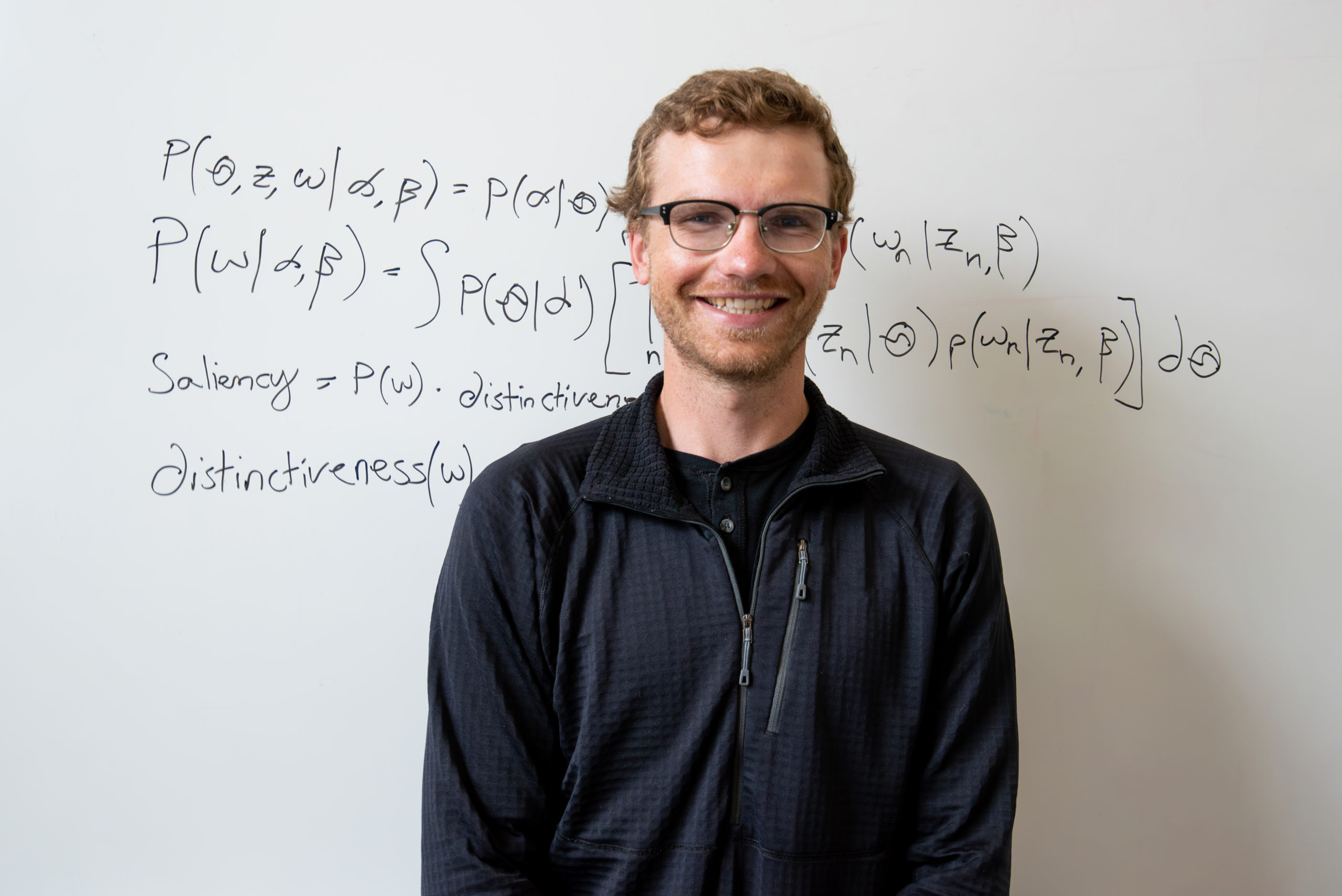 Fletcher Ouren, a master's student in the Department of Systems Engineering, stands in front of a whiteboard with a mathematical equation partly obscured behind him.
