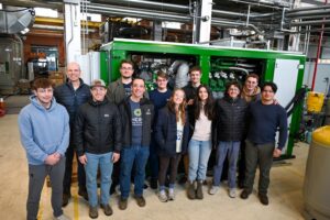 A team of researchers stand in front of the 2G engine in the Powerhouse