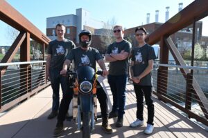 The Roam team with the motorcycle on the bridge by the Powerhouse