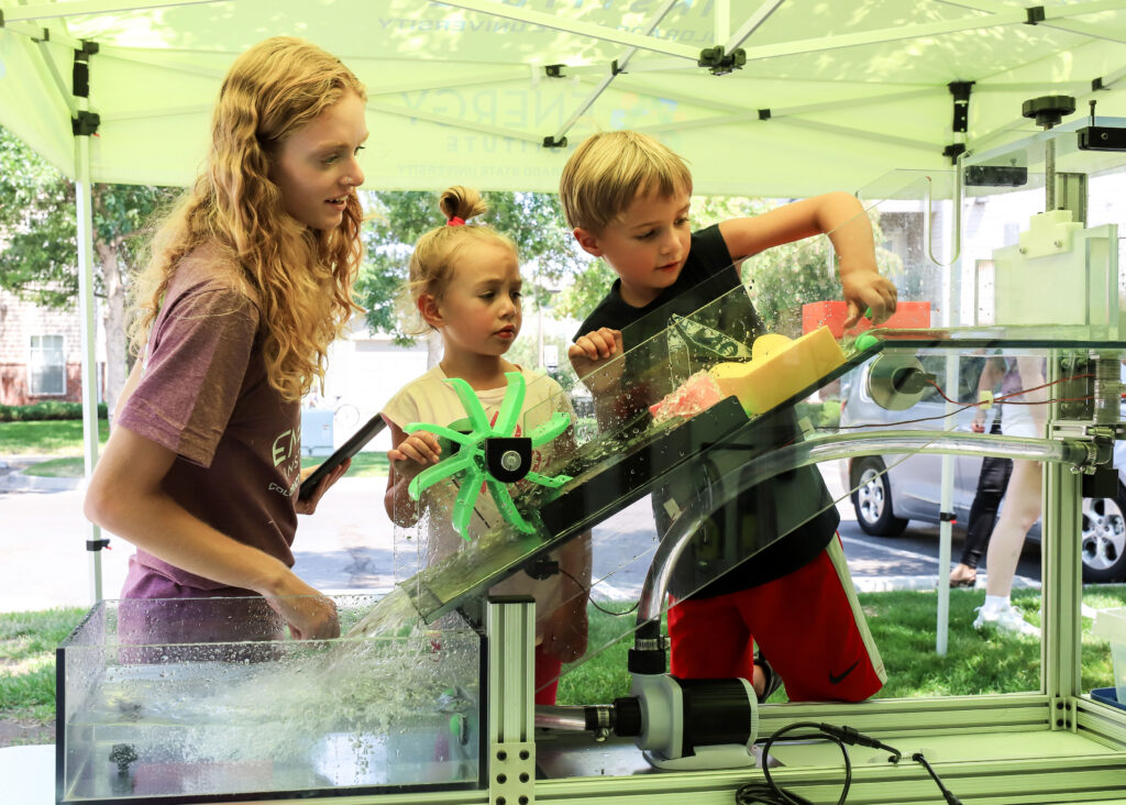 A mobile classroom team member helps two children complete a hydroflume activity