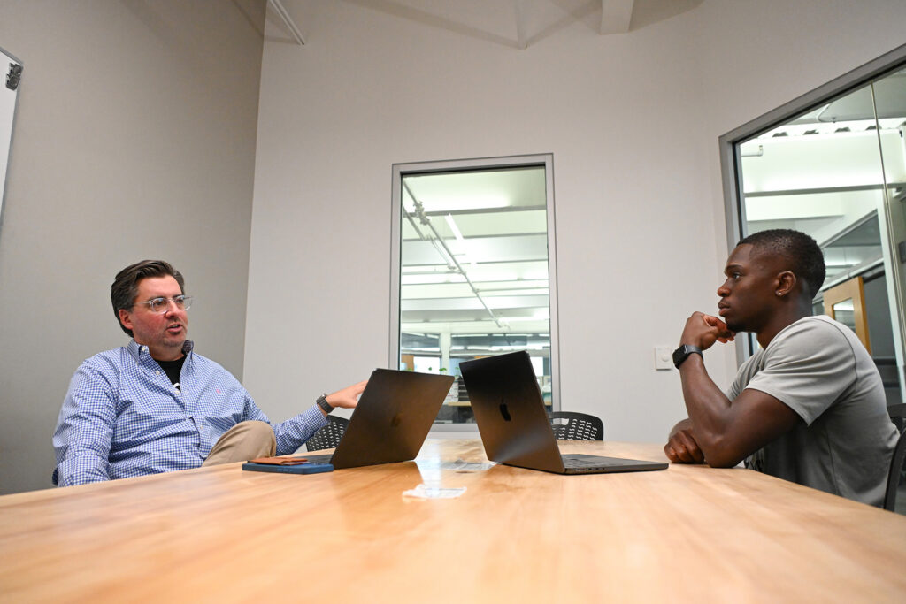 Two people meet and talk in a conference room.