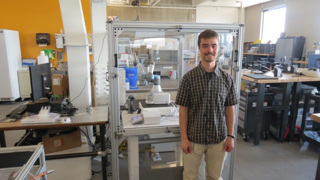 Gabe Neymark in front of the robotic system in the lab.